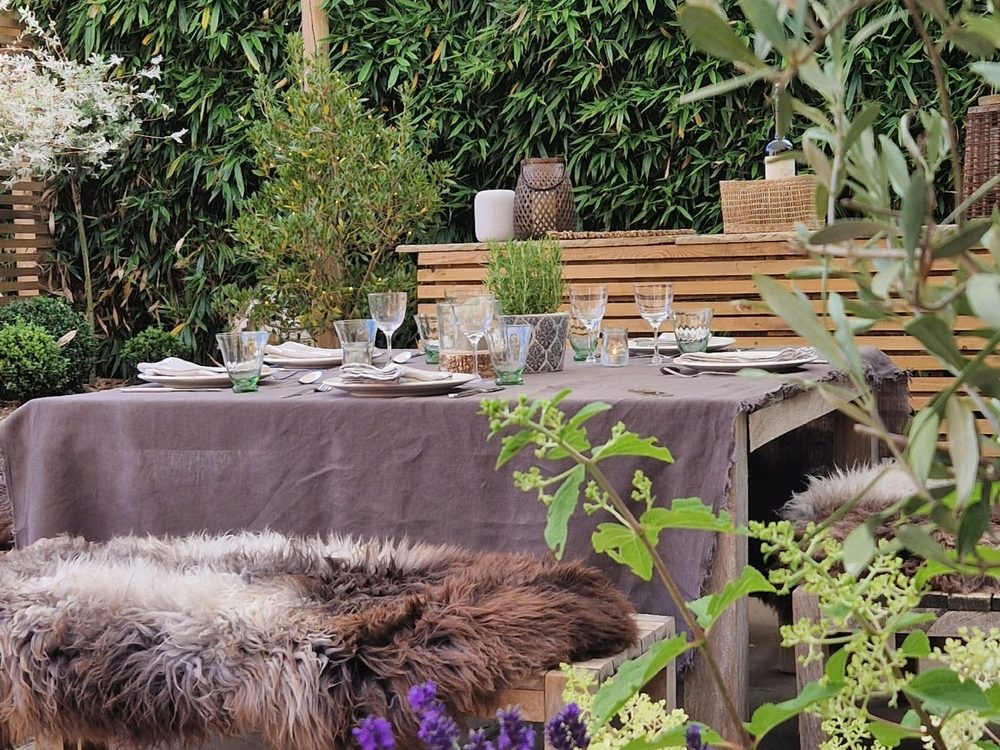 Outdoor dining terrace with table set under a shade sail